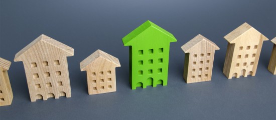 Row of wooden toy houses on a blue surface, with a bright green house in the center.