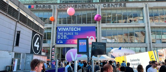 Crowd at a tech expo outside a convention center with a large ViveTech banner and colorful balloons.