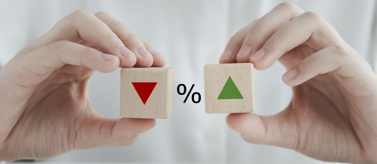 Hands hold two wooden blocks, one with a red down triangle and the other with a green up triangle, separated by a percent sign, signaling percentage change.