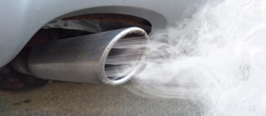 Car exhaust pipe emitting white smoke from a vehicle’s tailpipe near the ground area.