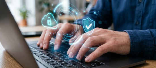 Person typing on a laptop with glowing cybersecurity icons (cloud lock and shield) illustrating data protection.