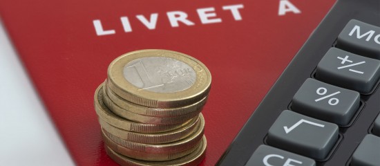 k4_24747392 Stack of coins resting on a red Livret A savings booklet beside a calculator