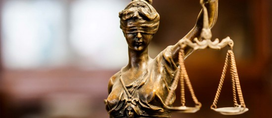 k4_24769804 Bronze statue of Lady Justice, blindfolded, holding the scales in a courtroom-like setting